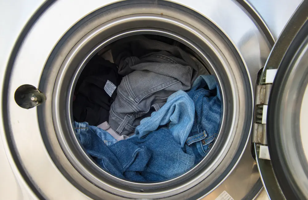 Close-up view of a large-capacity commercial washing machine drum with clothes washing inside