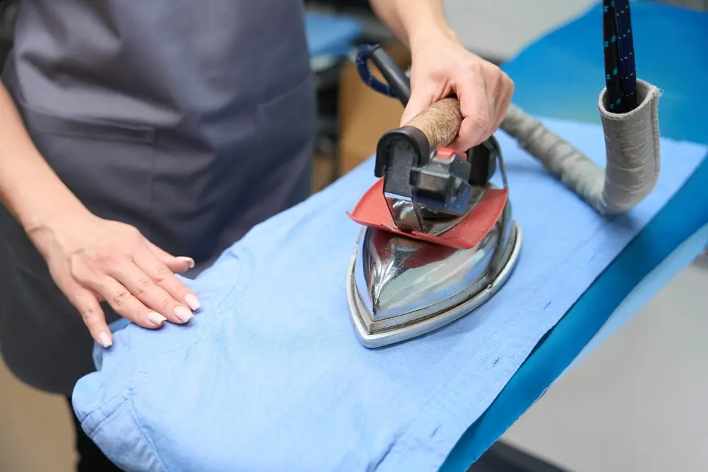 Professional tailor carefully ironing denim fabric on an ironing board