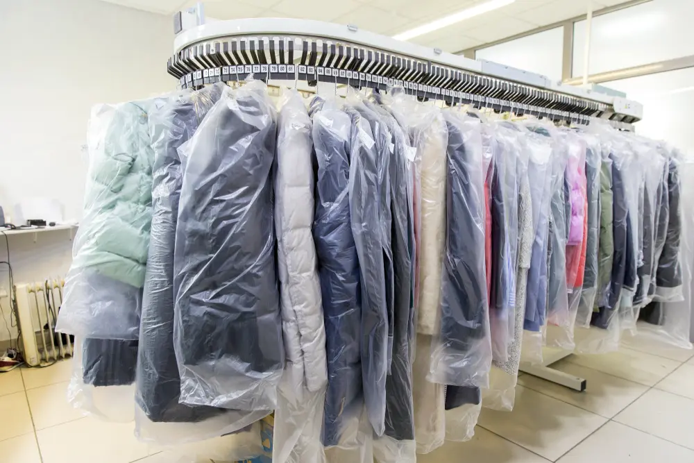 Clean clothes in plastic protective covers hanging neatly after professional dry cleaning